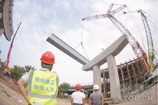 紅易-滬昆跨線橋跨滬昆高速公路主跨架梁施工現(xiàn)場，一節(jié)節(jié)鋼箱梁被吊起安裝。（記者 方陽 攝）